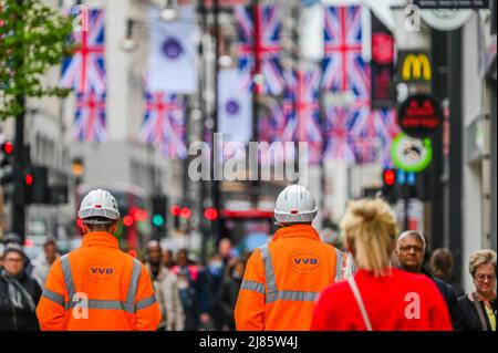 Londra, Regno Unito. 13th maggio 2022. I lavoratori della Elizabeth Line (ferrovia trasversale) prendono un freno da Bond Street Staion, Che è l'unica stazione ancora a ricevere l'approvazione di sicurezza per aprire - Oxford Street rimane occupato, nonostante il costo di vita crisi.While di cui sopra continuano i preparativi per la celebrazione del Giubileo del platino di HM la regina Elisabetta come Unione Jacks sono ora stati messi in su dall'altra parte della strada. Credit: Guy Bell/Alamy Live News Foto Stock