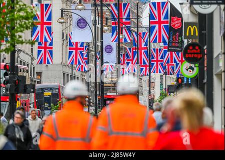 Londra, Regno Unito. 13th maggio 2022. I lavoratori della Elizabeth Line (ferrovia trasversale) prendono un freno da Bond Street Staion, Che è l'unica stazione ancora a ricevere l'approvazione di sicurezza per aprire - Oxford Street rimane occupato, nonostante il costo di vita crisi.While di cui sopra continuano i preparativi per la celebrazione del Giubileo del platino di HM la regina Elisabetta come Unione Jacks sono ora stati messi in su dall'altra parte della strada. Credit: Guy Bell/Alamy Live News Foto Stock