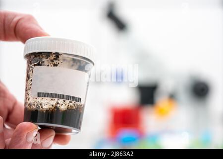 l'ecologo scientifico contiene un contenitore con un campione di terreno per analisi chimiche e microbiologiche Foto Stock