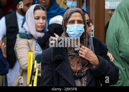 Una donna musulmana che indossa una maschera lascia una moschea dopo aver assistito alle preghiere del mattino. Foto Stock
