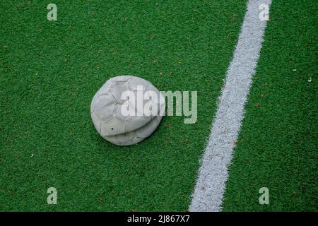 pallone da calcio sgonfio sul campo sportivo verde erba. Impossibile giocare. Foto Stock