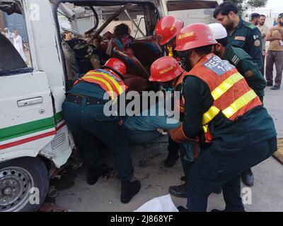 Gujranwala. 13th maggio 2022. La foto del cellulare scattata il 13 maggio 2022 mostra i soccorritori che lavorano ad un luogo di incidente stradale nel distretto di Gujranwala della provincia orientale del Punjab del Pakistan. Almeno 12 persone sono state uccise e 10 altre ferite in un incidente stradale il venerdì nel distretto di Gujranwala, nella provincia orientale del Punjab in Pakistan, i media locali hanno riferito. Secondo i rapporti, l'incidente si è verificato nelle prime ore in cui un camion del dumper che accelera si è schiantato con due furgoni passeggeri uno dopo l'altro sulla strada di Hafizabad vicino alla zona di Kot Ladha di Gujranwala. Credit: Str/Xinhua/Alamy Live News Foto Stock