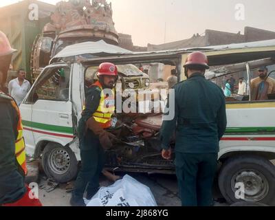 Gujranwala. 13th maggio 2022. La foto del cellulare scattata il 13 maggio 2022 mostra i soccorritori che lavorano ad un luogo di incidente stradale nel distretto di Gujranwala della provincia orientale del Punjab del Pakistan. Almeno 12 persone sono state uccise e 10 altre ferite in un incidente stradale il venerdì nel distretto di Gujranwala, nella provincia orientale del Punjab in Pakistan, i media locali hanno riferito. Secondo i rapporti, l'incidente si è verificato nelle prime ore in cui un camion del dumper che accelera si è schiantato con due furgoni passeggeri uno dopo l'altro sulla strada di Hafizabad vicino alla zona di Kot Ladha di Gujranwala. Credit: Str/Xinhua/Alamy Live News Foto Stock