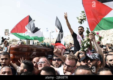 Gerusalemme, Israele. 13th maggio 2022. I lutto palestinesi trasportano la scrigno del reporter ucciso al Jazeera, Shireen Abu Akleh, durante la sua processione funebre al suo luogo di riposo finale. Abu Akleh, 51, figura di spicco nel servizio di stampa arabo del canale al-Jazeera, è stato ucciso il 11 maggio durante un confronto tra soldati israeliani e palestinesi nella città di Jenin, in Cisgiordania. Credit: Ilia Yefimovich/dpa/Alamy Live News Foto Stock