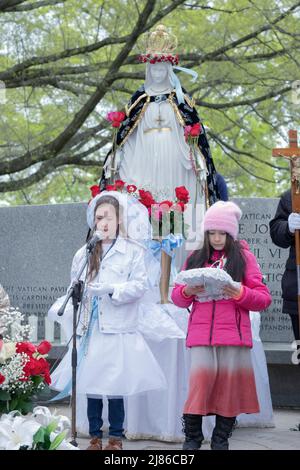 Una bambina di 8 anni conduce una festa della mamma "May incoroning" servizio di devoti cattolici romani in un parco a Queens, New York City Foto Stock