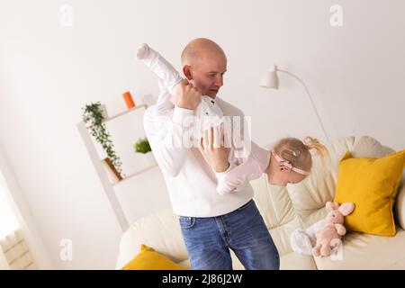 Bambino con impianti cocleari che gioca con suo padre a casa. Sordità e tecnologia medica concetto Foto Stock
