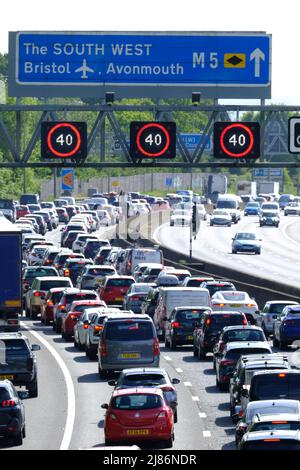 Bristol, Regno Unito. 13th maggio 2022. La fuga del venerdì soleggiato conduce alla congestione sull'autostrada M5. 40 MPH sono in vigore limitazioni di velocità sul tratto gestito dell'autostrada M5 a Filton a causa del volume di traffico che si dirige verso sud verso Devon e Cornovaglia. Nonostante l'elevato costo del carburante, le persone continuano a fare affidamento sulle loro auto. Autostrade Inghilterra rapporto velocità di 12 MPH. Credit: JMF News/Alamy Live News Foto Stock