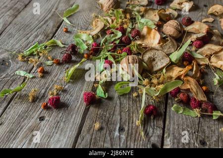 Deliziose prelibatezze essiccate: Pezzi secchi di tiglio, fianchi di rose, pere, lamponi, mele e noci snack su sfondo di legno. Foto Stock