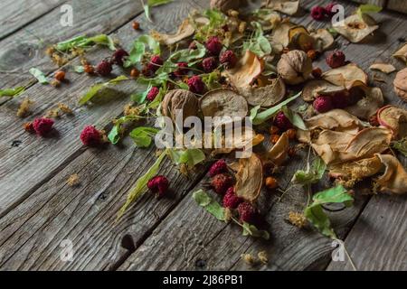 Deliziose prelibatezze essiccate: Pezzi secchi di tiglio, fianchi di rose, pere, lamponi, mele e noci snack su sfondo di legno. Foto Stock