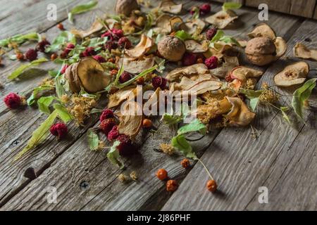 Deliziose prelibatezze essiccate. Pezzi secchi di tiglio, fianchi di rose, pere, lamponi, mele e noci snack su sfondo di legno. Foto Stock