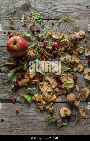 Deliziose prelibatezze essiccate. Pezzi secchi di tiglio, fianchi di rose, pere, lamponi, mele e noci snack su sfondo di legno. Foto Stock