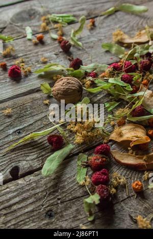 Deliziose prelibatezze essiccate. Pezzi secchi di tiglio, fianchi di rose, pere, lamponi, mele e noci snack su sfondo di legno. Foto Stock