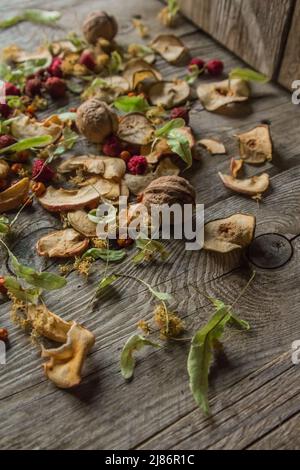 Deliziose prelibatezze essiccate. Pezzi secchi di tiglio, fianchi di rose, pere, lamponi, mele e noci snack su sfondo di legno. Foto Stock