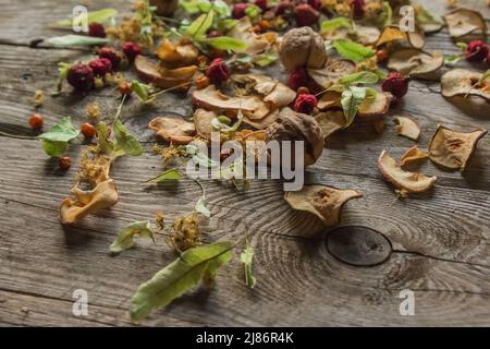 Deliziose prelibatezze essiccate. Pezzi secchi di tiglio, fianchi di rose, pere, lamponi, mele e noci snack su sfondo di legno. Foto Stock