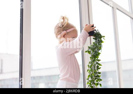 Bambino divertente con impianto cocleare seduta a casa e mangiare. Ascolta il concetto di tecnologia innovativa di aiuto e medicina Foto Stock