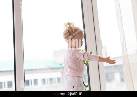 Bambino divertente con impianto cocleare seduta a casa e mangiare. Ascolta il concetto di tecnologia innovativa di aiuto e medicina Foto Stock