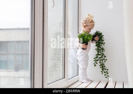 Bambino divertente con impianto cocleare seduta a casa e mangiare. Ascolta il concetto di tecnologia innovativa di aiuto e medicina Foto Stock