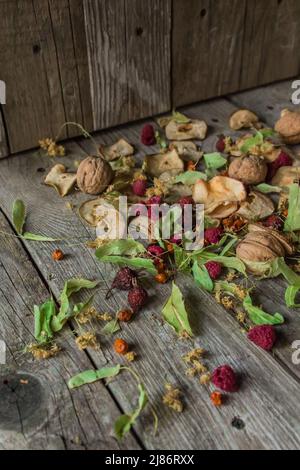 Deliziose prelibatezze essiccate. Pezzi secchi di tiglio, fianchi di rose, pere, lamponi, mele e noci snack su sfondo di legno. Foto Stock