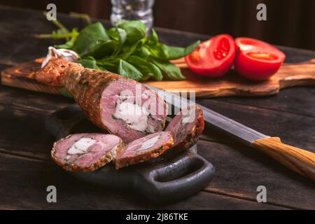 Affettare da una carne di tacchino artigianale fatta in casa, bollita e affumicata con l'aggiunta di filetto di pollo nella pelle di una gamba di pollo con un osso Foto Stock