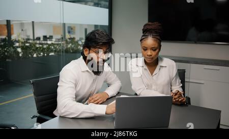 Team multietnico di affari diverse persone brainstorm in ufficio due uomini arabi e donna africana utilizzando computer portatile discutere di startup colleghi Foto Stock