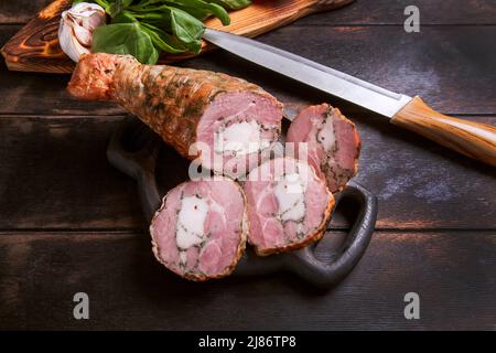 Affettare da una carne di tacchino artigianale fatta in casa, bollita e affumicata con l'aggiunta di filetto di pollo nella pelle di una gamba di pollo con un osso Foto Stock