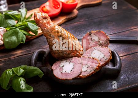 Affettare da una carne di tacchino artigianale fatta in casa, bollita e affumicata con l'aggiunta di filetto di pollo nella pelle di una gamba di pollo con un osso Foto Stock