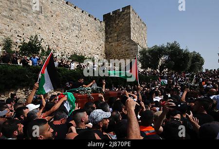 Gerusalemme, Medio Oriente. 13th maggio 2022. I palestinesi ondano bandiere nazionali mentre trasportano la scrigno del giornalista ucciso al-Jazeera Shireen Abu Aklel durante la sua processione funebre dalla chiesa verso il cimitero, a Gerusalemme, Israele, venerdì 13 maggio 2022. Abu Akleh è stato ucciso il 11th maggio, mentre copriva un raid nella Cisgiordania occupata da Israele. Foto di Jamal Awad/UPI Credit: UPI/Alamy Live News Foto Stock