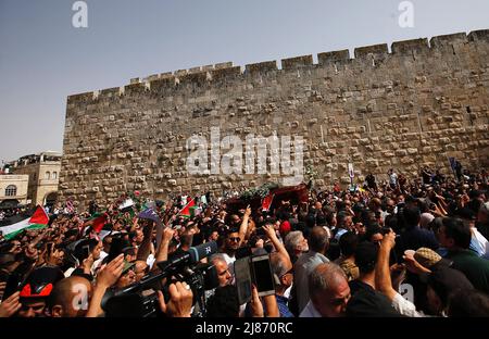 Gerusalemme, Medio Oriente. 13th maggio 2022. I palestinesi ondano bandiere nazionali mentre trasportano la scrigno del giornalista ucciso al-Jazeera Shireen Abu Aklel durante la sua processione funebre dalla chiesa verso il cimitero, a Gerusalemme, Israele, venerdì 13 maggio 2022. Abu Akleh è stato ucciso il 11th maggio, mentre copriva un raid nella Cisgiordania occupata da Israele. Foto di Jamal Awad/UPI Credit: UPI/Alamy Live News Foto Stock