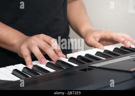 dettaglio delle mani di un giovane latino che pratica pianoforte su un sintetizzatore. ragazzo in classe musicale. concetto musicale. Foto Stock