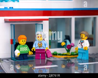 Tambov, Federazione Russa - 11 febbraio 2022 una minifcifra di Lego ragazzo con un calco sul braccio e sua nonna che cammina fuori da un ospedale e un medico Foto Stock