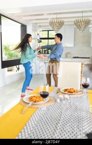 Giovane coppia asiatica che si diverse a ballare mentre si pranzava a casa Foto Stock
