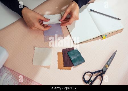 in un notebook scrivono splendidi marinai con capelli lunghi. il sarto crea una collezione di abiti. abbigliamento giovane donna designer con cui lavorare Foto Stock