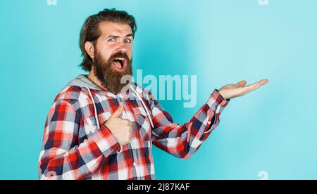 L'uomo felice bearded tiene qualcosa sul palmo aperto della mano e mostra il pollice in su. Sconti e sconti stagionali Foto Stock