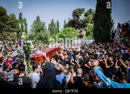 Gerusalemme, Israele. 13th maggio 2022. I lutto trasportano la bara del giornalista al Jazeera Shireen Abu Akleh durante la processione funebre. Abu Akleh è stato ucciso il mercoledì mattina in Cisgiordania occupata mentre stava coprendo un raid israeliano sulla città di Jenin. Testimoni hanno detto che è stata uccisa da un soldato israeliano. L'esercito israeliano ha detto venerdì che, mentre era possibile, la sig.ra Abu Akleh è stata erroneamente uccisa dal fuoco israeliano; le sue indagini iniziali hanno suggerito che potrebbe essere stata colpita anche da un pistolero palestinese. Credit: SOPA Images Limited/Alamy Live News Foto Stock