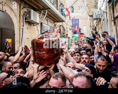 Gerusalemme, Israele. 13th maggio 2022. I lutto trasportano la bara del giornalista al Jazeera Shireen Abu Akleh durante la processione funebre. Abu Akleh è stato ucciso il mercoledì mattina in Cisgiordania occupata mentre stava coprendo un raid israeliano sulla città di Jenin. Testimoni hanno detto che è stata uccisa da un soldato israeliano. L'esercito israeliano ha detto venerdì che, mentre era possibile, la sig.ra Abu Akleh è stata erroneamente uccisa dal fuoco israeliano; le sue indagini iniziali hanno suggerito che potrebbe essere stata colpita anche da un pistolero palestinese. Credit: SOPA Images Limited/Alamy Live News Foto Stock