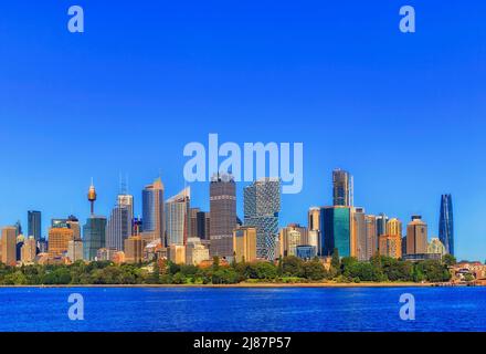 Skyline del CBD di Sydney sulle rive verdi del parco del porto in una giornata di sole - alti uffici torri architettura moderna e punti di riferimento. Foto Stock