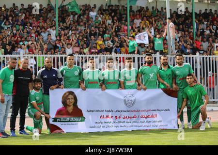 Medio Oriente. 13th maggio 2022. 11 maggio 2022, Città di Gaza, striscia di Gaza, Palestina: Durante una partita nella lega di calcio nella striscia di Gaza tra al-Shuja'iya Club 'il colore verde'' e il club Shabab Rafah 'il colore blu', i tifosi hanno alzato una foto del martire Sherine Abu Aqleh, Che questa mattina è stato martirizzato a Jenin mentre svolgeva la sua professione, allo Yarmouk Stadium di Gaza City, dove la partita si è conclusa in un pareggio negativo. (Credit Image: © Mahmoud Ajjour/Quds Net News via ZUMA Press Wire) Credit: ZUMA Press, Inc./Alamy Live News Foto Stock