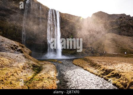 Una magica mattinata invernale alla cascata di Seljalandsfoss, il sole sorge sulle scogliere dietro la cascata, vicino alla Route 1 / Ring Road, regione meridionale, Islanda Foto Stock