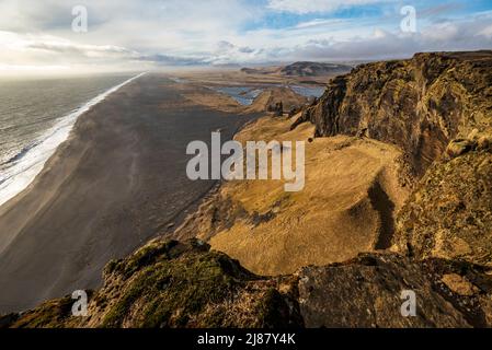 Vista panoramica della sabbia di lava nera della spiaggia di Dyrhólafjara, Islanda, vista dalla roccia degli uccelli di Dyrhólaey con le sue scogliere giganti, vicino a Vík í Mýrdal Foto Stock
