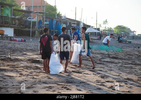 Un gruppo di persone locali alla spiaggia di Batu Bolong a Canggu, Bali, Indonesia, che raccoglie rifiuti e rifiuti sulla spiaggia e li mette in sacchi bianchi. Foto Stock