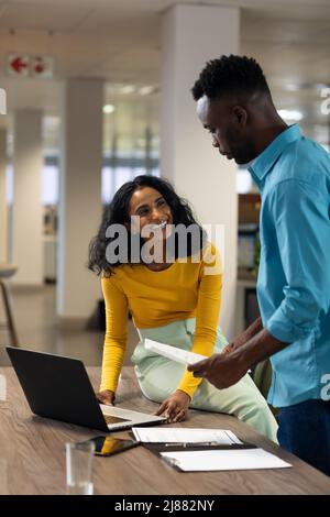 Sorridente donna d'affari biraciale guardando l'uomo d'affari afro-americano durante la riunione Foto Stock