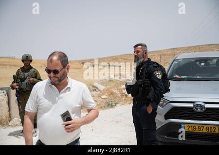 Masafer Yatta, Palestina. 13th maggio 2022. Ofer Cassif, un politico israeliano del Partito della Lista congiunta vicino ad un ufficiale di polizia che afferma che Cassif lo ha attaccato mentre gli ha impedito di spostare la sua auto - contro i suoi diritti di immunità. Una protesta di solidarietà contro gli attivisti di pace israeliani e i residenti di Masafer Yatta che si trovano di fronte a una minaccia immediata di deportazione. Un recente verdetto della Corte Suprema israeliana stabilisce che otto comunità siano espulse da tempo in Palestina da Masafer Yatta. Credit: SOPA Images Limited/Alamy Live News Foto Stock