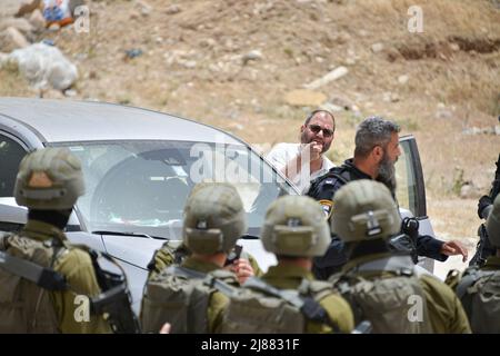 Masafer Yatta, Palestina. 13th maggio 2022. Ofer Cassif, un politico israeliano del Partito della Lista congiunta vicino ad un ufficiale di polizia che afferma che Cassif lo ha attaccato mentre gli ha impedito di spostare la sua auto - contro i suoi diritti di immunità. Una protesta di solidarietà contro gli attivisti di pace israeliani e i residenti di Masafer Yatta che si trovano di fronte a una minaccia immediata di deportazione. Un recente verdetto della Corte Suprema israeliana stabilisce che otto comunità siano espulse da tempo in Palestina da Masafer Yatta. (Foto di Matan Golan/SOPA Images/Sipa USA) Credit: Sipa USA/Alamy Live News Foto Stock