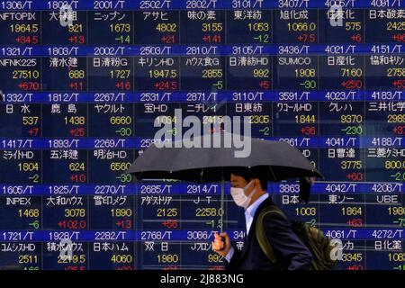 Tokyo, Giappone. 13th maggio 2022. Un uomo che tiene un ombrello cammina di fronte a un quadro elettrico mostrando Nikkei indice un brokerage a Tokyo. (Foto di James Matsumoto/SOPA Images/Sipa USA) Credit: Sipa USA/Alamy Live News Foto Stock