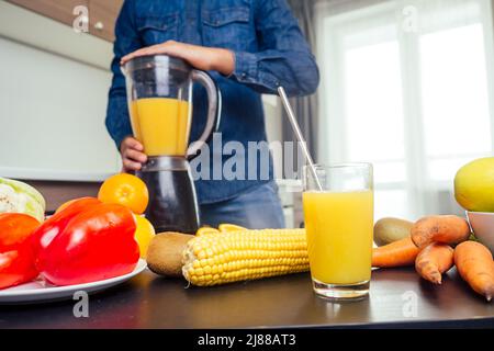 il giovane indiano in cucina prepara un succo d'arancia fresco Foto Stock