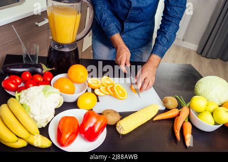 il giovane indiano in cucina prepara un succo d'arancia fresco Foto Stock