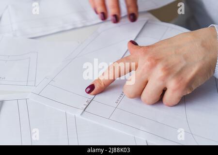 Donna su misura durante il lavoro su modelli di cucitura. Unire i dettagli della carta per vestire Foto Stock