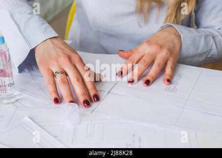 Donna su misura durante il lavoro su modelli di cucitura. Unire i dettagli della carta per vestire Foto Stock