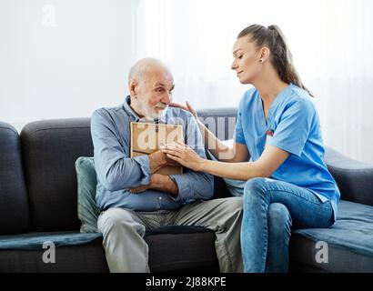 infermiera medico cure senior immagine caregiver triste aiuto assistenza pensione casa memoria nostalgia uomo anziano Foto Stock