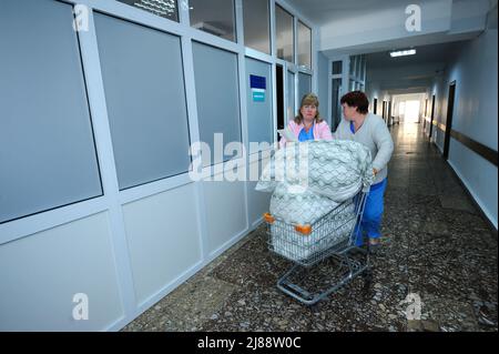 Infermiere in un camici da laboratorio tirando un carrello con biancheria in una lobby di unità chirurgica di un ospedale. Gennaio 12, 2019. Clinica regionale di Kiev 1. Kiev, Ucraina Foto Stock